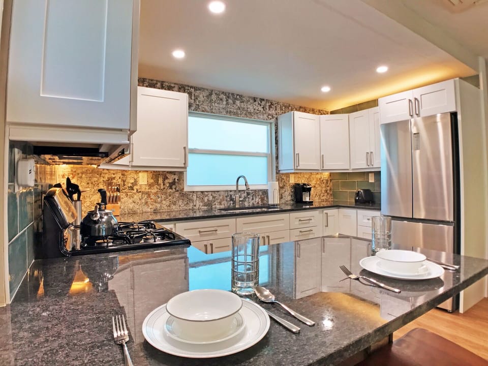 Kitchen with white cabinets, dark stone countertops, and stainless refrigerator