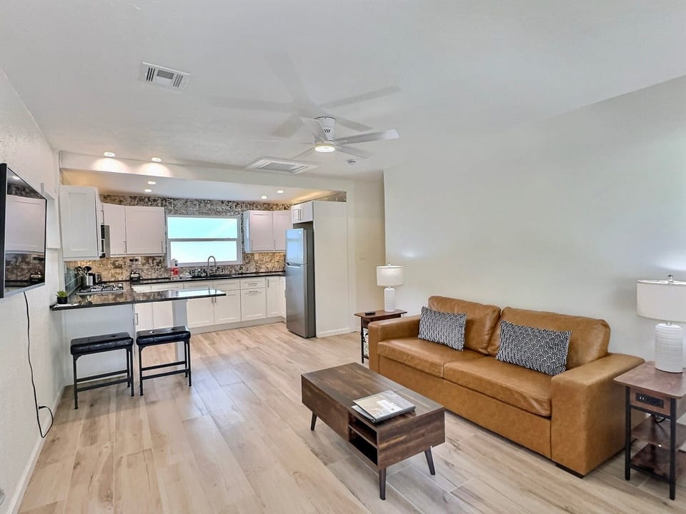 Open-plan living area with sofa, coffee table, and kitchen visible in background