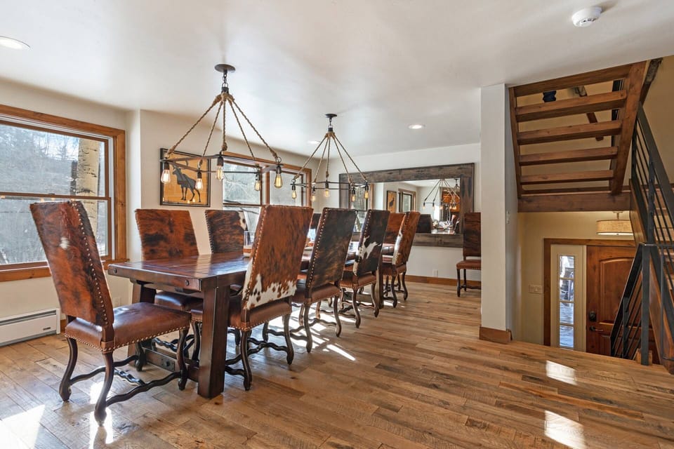 Stunning dining table with high back chairs and rustic chandeliers, fit for 10 guests.