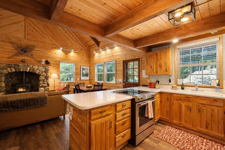 Gather in your rustic-chic kitchen where warm wood beams and stone fireplace create cozy charm for cooking and connecting.