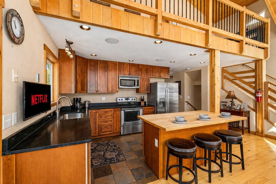Your spacious kitchen features warm wood cabinets, granite counters, and a breakfast bar perfect for morning coffee or casual meals together.