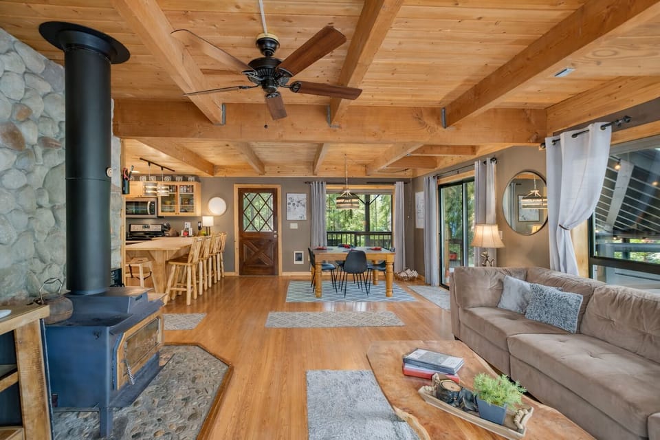 Unwind in your warm, rustic retreat with exposed beams, crackling fireplace, and open-concept living that flows from cozy couch to dining table to kitchen.