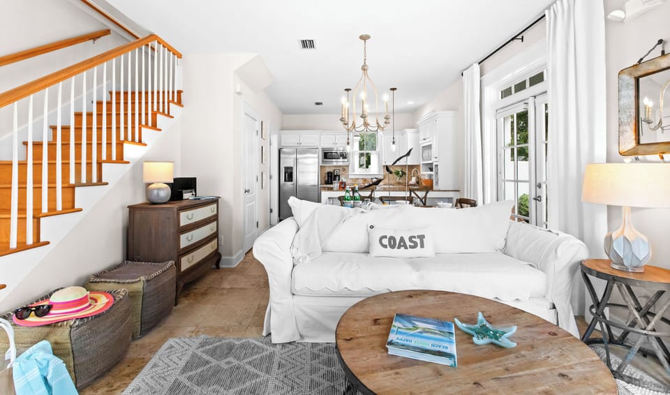 Sink into plush seating in your light-filled living space, where coastal charm meets open-concept comfort with a fully equipped kitchen just steps away.