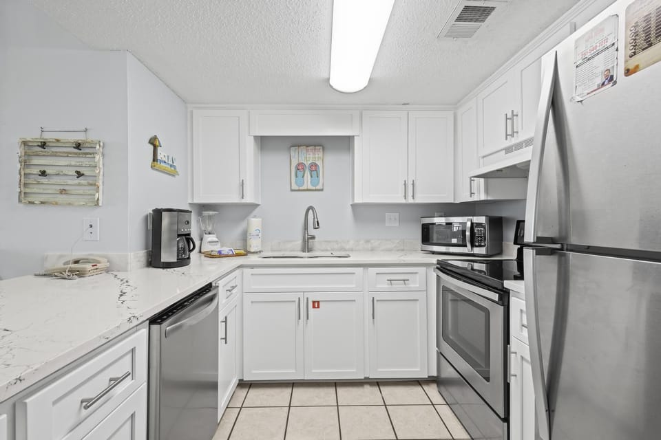 Kitchen - The kitchen features stainless appliances, which include a dishwasher, smooth cooktop range with oven, microwave, and a refrigerator with ice maker. Each cabinet is fully stocked with all items needed for meal prepping.