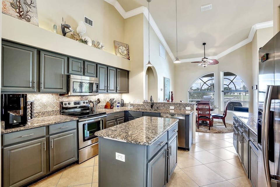 Granite countertops stretch across the kitchen island and counters, complemented by gray cabinetry and stainless steel appliances.