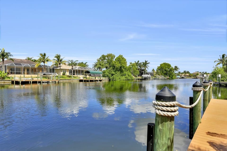 Private dock overlooking the calm wide direct Gulf access canal lined with palm trees.
