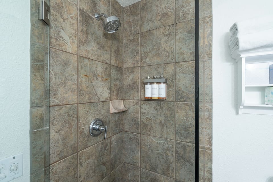 Step into a beautifully tiled walk-in shower with rainfall showerhead, built-in niche for your toiletries, and fresh towels ready for your arrival.