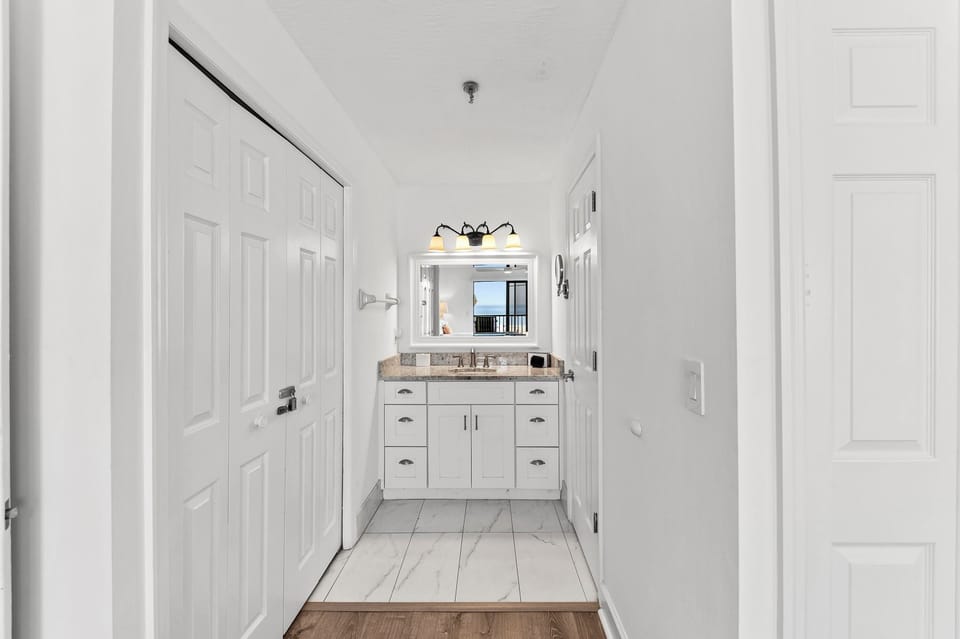 Step into your pristine bathroom featuring elegant white cabinetry, granite countertops, and stylish lighting that creates the perfect morning routine.