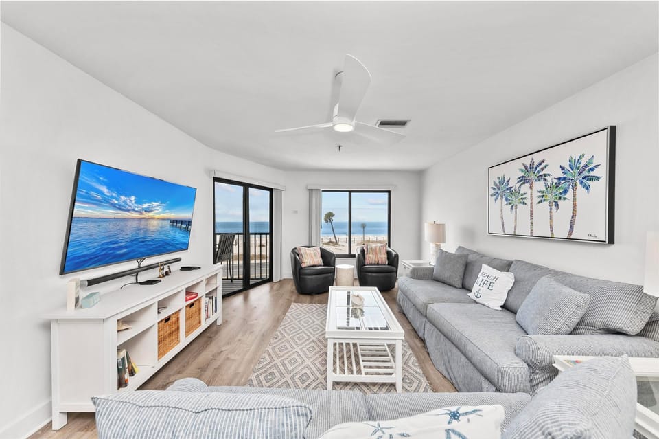 Your bright beachfront living room offers stunning ocean views through floor-to-ceiling windows, plush seating, and coastal décor perfect for relaxing after beach days.
