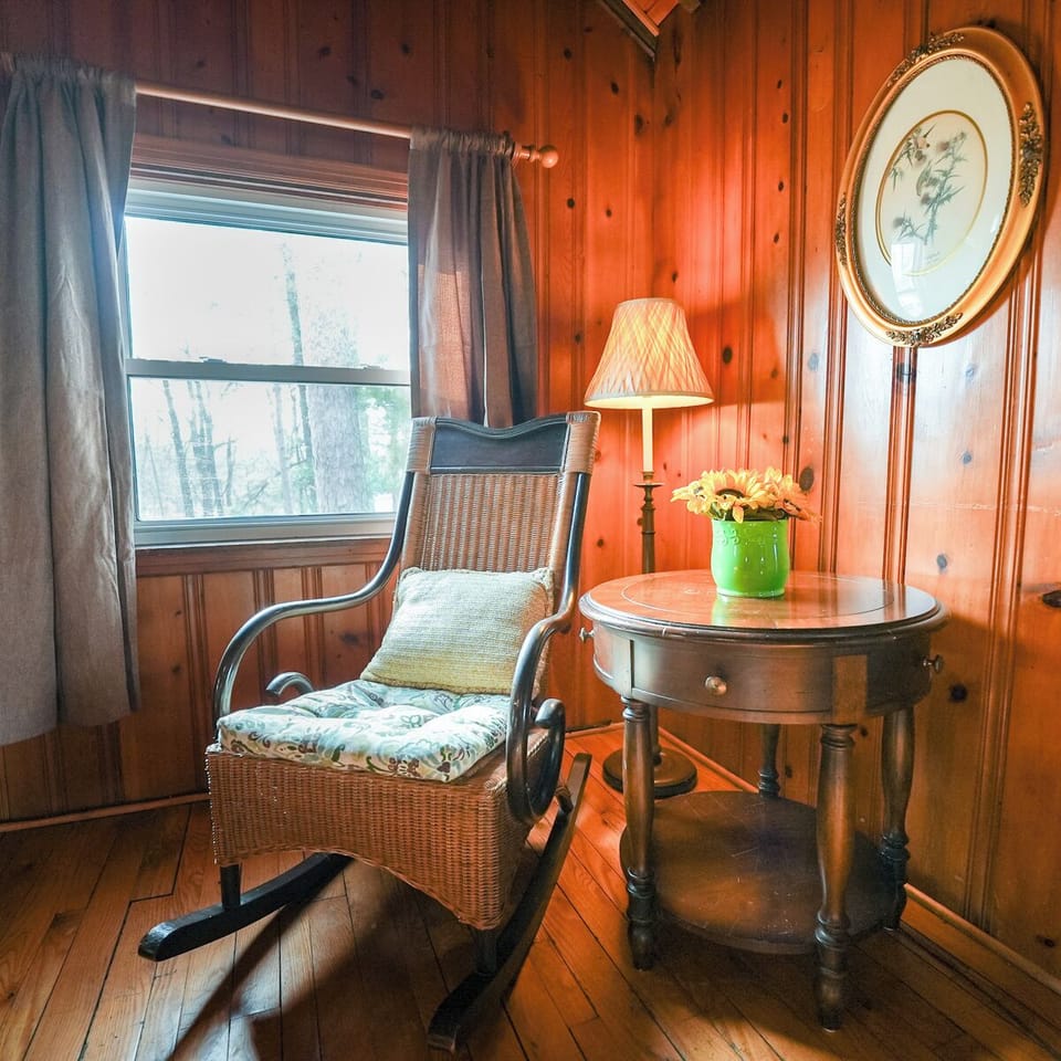 Settle into your charming reading nook with warm wood paneling, soft lamplight, and peaceful garden views through your window.