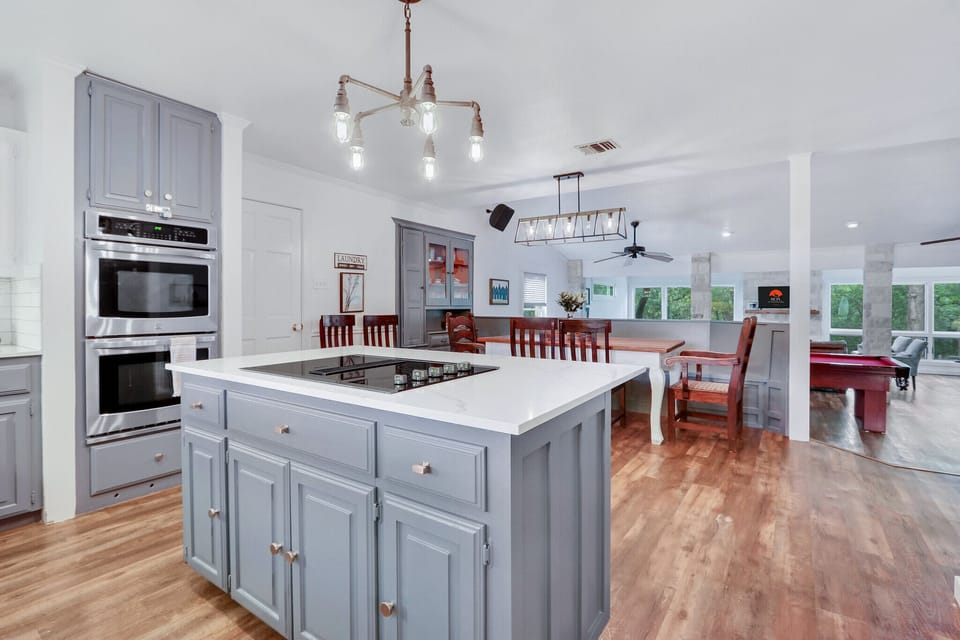 View of kitchen island looking toward the dining table and living room beyond.The doorway to the left of the table leads to the laundry room and half bath.