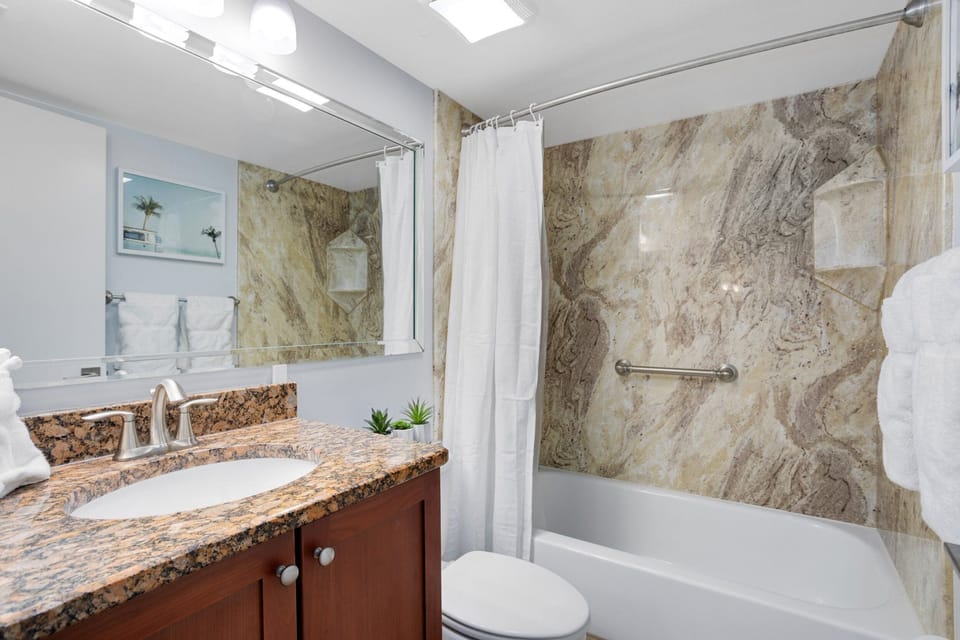 Luxurious bathroom featuring a granite vanity and a stone-accented bathtub