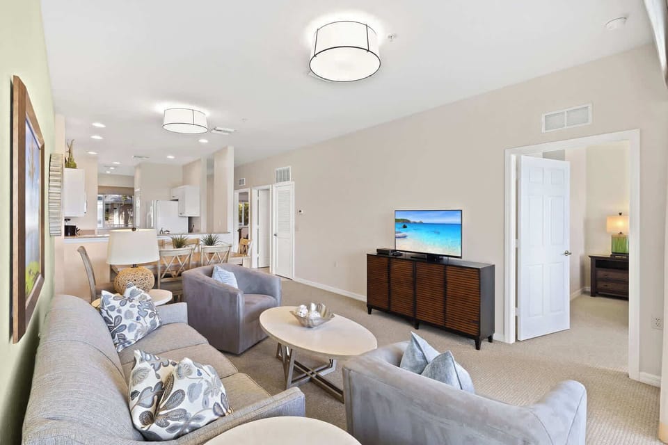 Living Room with Flat Screen TV, Fan, and Entrance to Lanai Area with Lake and Golf Views; Just Renovated!