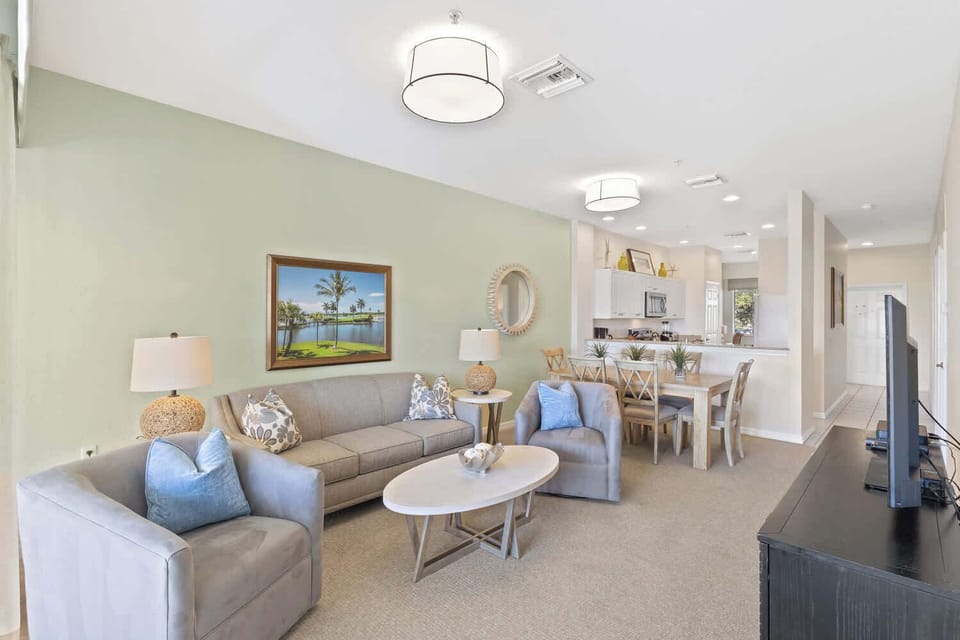 Living Room with Flat Screen TV, Fan, and Entrance to Lanai Area with Lake and Golf Views; Just Renovated!