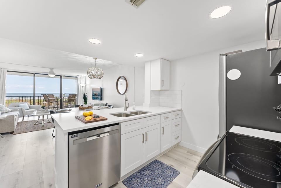 Modern kitchen with stainless steel appliances, sleek white cabinetry, and an ocean-view window.
