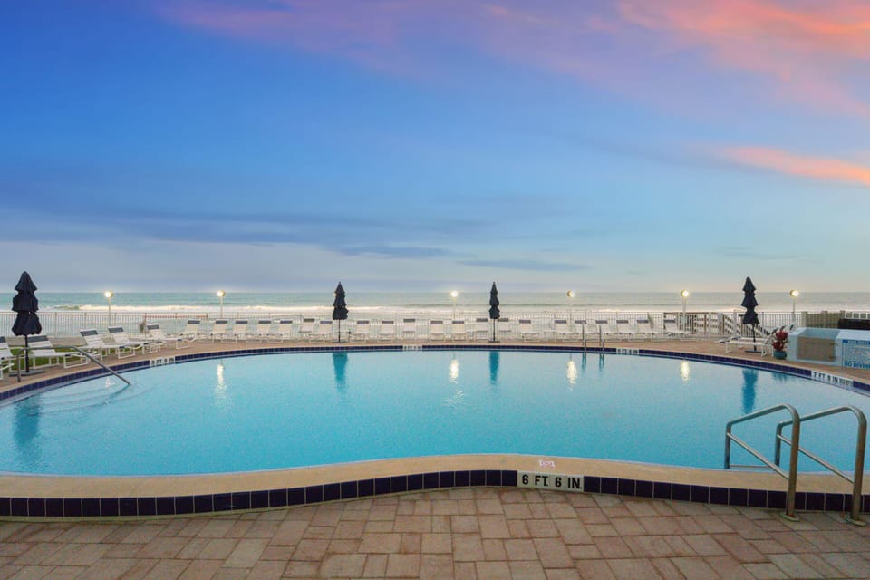 Heated oceanfront swimming pool with surrounding lounge chairs, spacious deck area, and direct views of the shoreline.