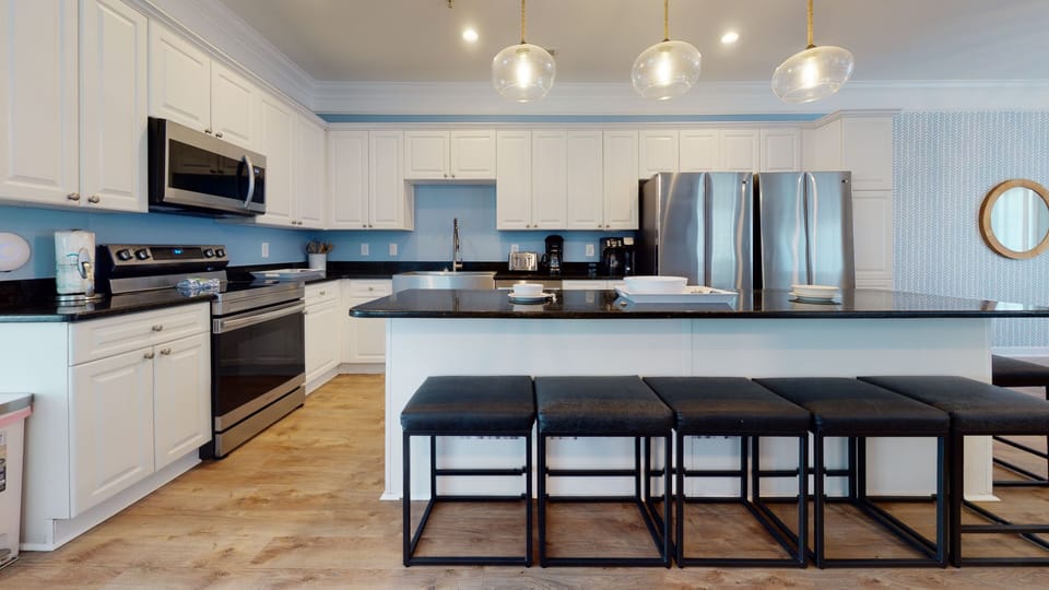 Fully equipped with stainless steel appliances and a sleek island bar.