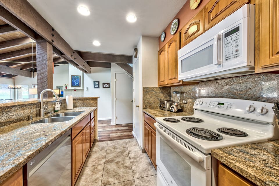 This fully-equipped kitchen features granite countertops, modern appliances, and rustic wood beams, perfect for creating memorable meals together.