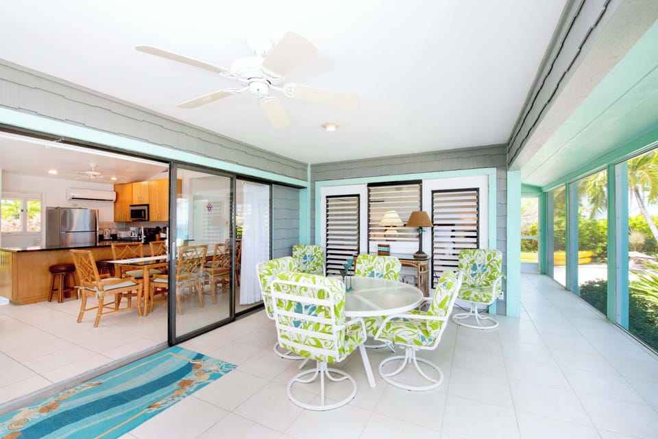 The screened porch comes furnished with a dining table and lounge area with sweeping ocean views.