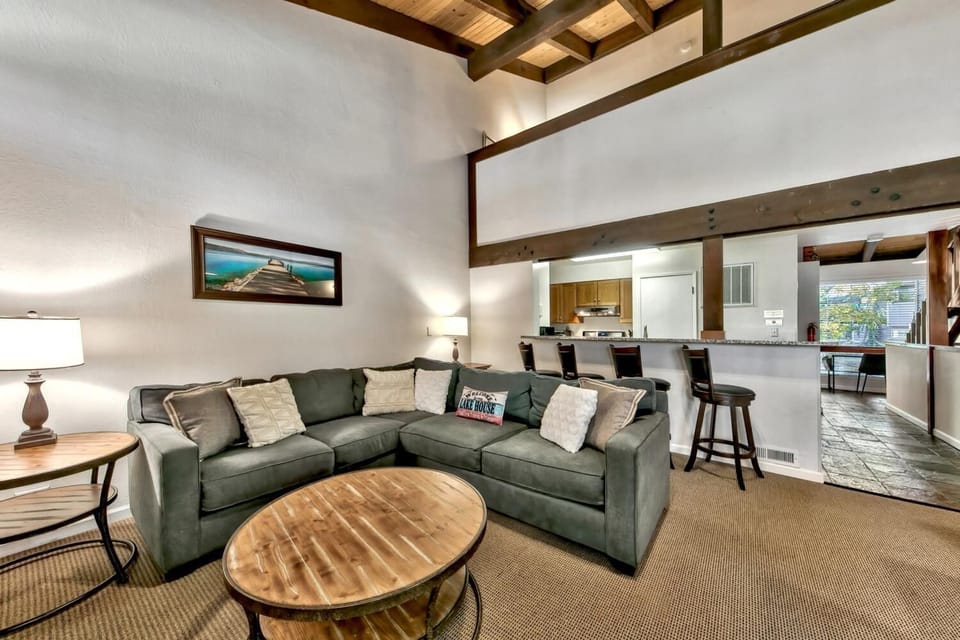 Unwind on your plush sectional sofa beneath stunning exposed beams while the open kitchen awaits your culinary adventures.
