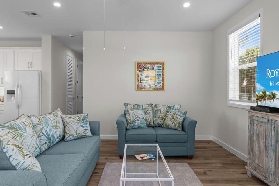 Bright and airy living room with coastal-inspired décor, comfy seating, and a flat-screen TV—perfect for relaxing after a day in the sun.