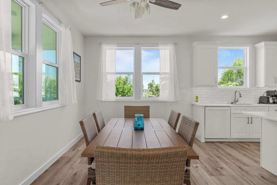 Charming dining area with woven chairs, natural light, and views of lush tropical greenery—ideal for enjoying meals with family and friends.