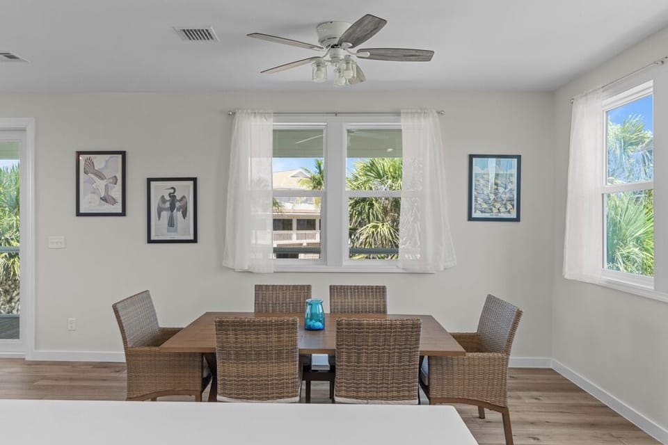 Charming dining area with woven chairs, natural light, and views of lush tropical greenery—ideal for enjoying meals with family and friends.