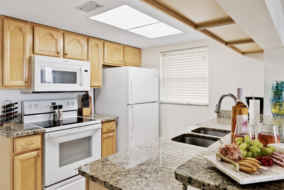 Fully stocked kitchen with granite countertops and wooden cabinetry.