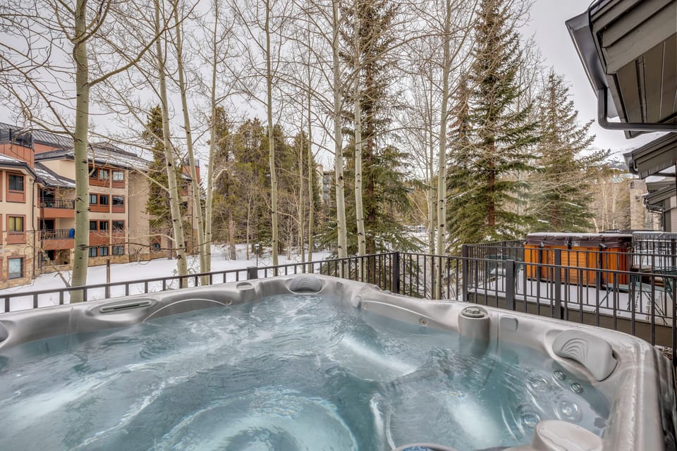 Sink into bubbling warmth while snow-dusted trees frame your private hot tub retreat on this peaceful balcony.