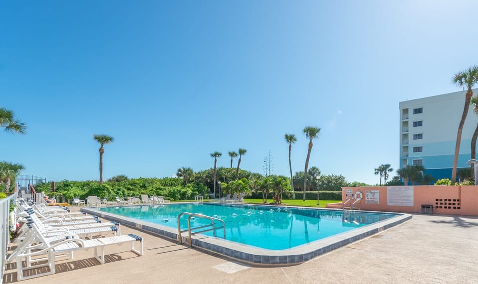 Expansive heated oceanfront pool, surrounded by lush greenery and scenic views.