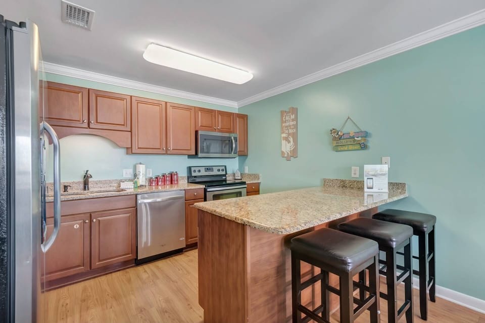 Fully equipped kitchen with three stools at the breakfast bar and plenty of counter space. Stocked with all necessary cookware and serving essentials.
