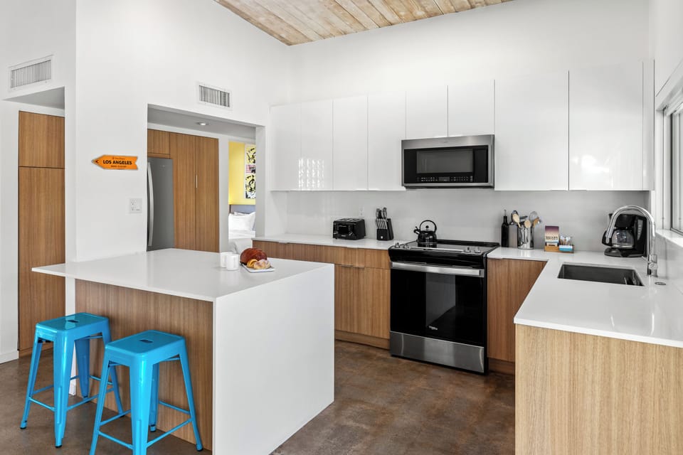 Your modern kitchen features sleek white countertops, wood-grain cabinets, and stainless steel appliances perfect for preparing meals during your stay.
