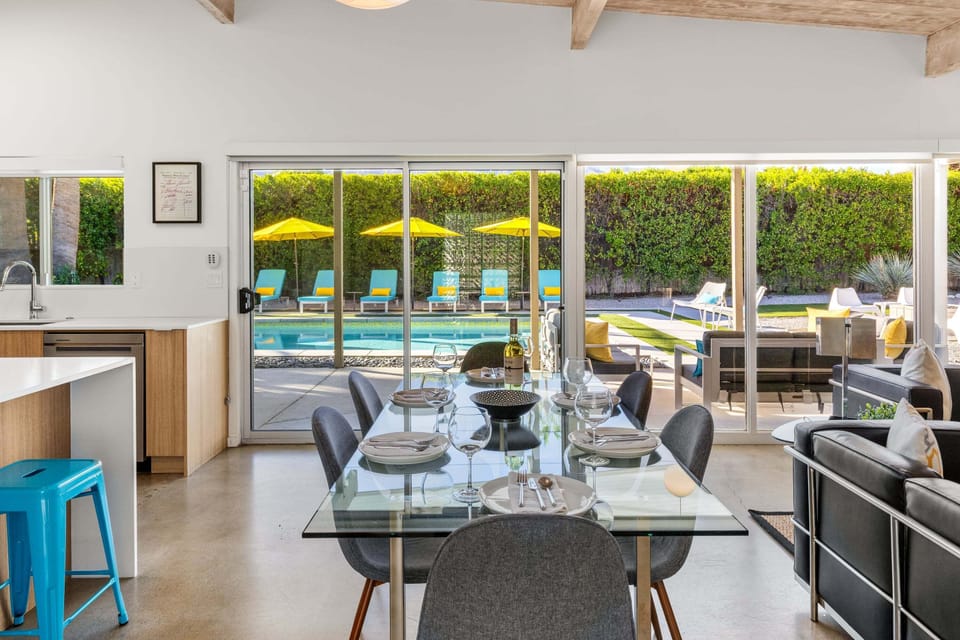 Your open dining space flows seamlessly to the sparkling pool through floor-to-ceiling glass doors, creating perfect indoor-outdoor living.