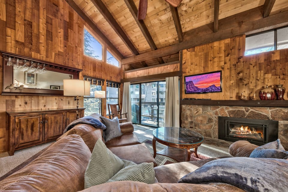 Sink into plush leather seating beside your crackling stone fireplace, where rustic wood beams frame cozy evenings of mountain relaxation.