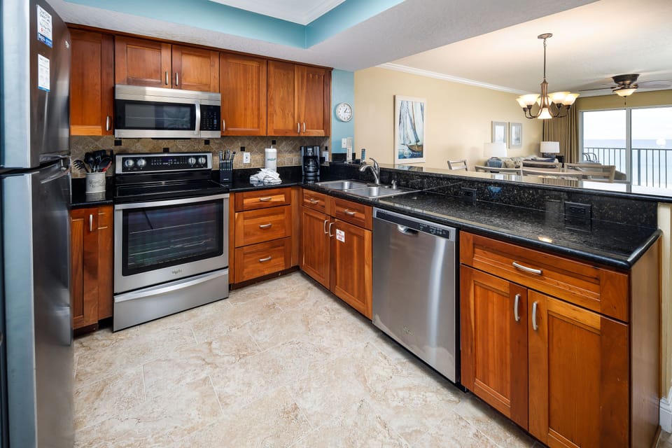 View of the kitchen - This updated kitchen is fully equipped for all of your cooking needs. Who wouldn't want to prepare a meal alongside our enticing emerald waters! Everything you need is right at your fingertips. Cherry stained cabinets and granite counter tops make up this charming palette.
