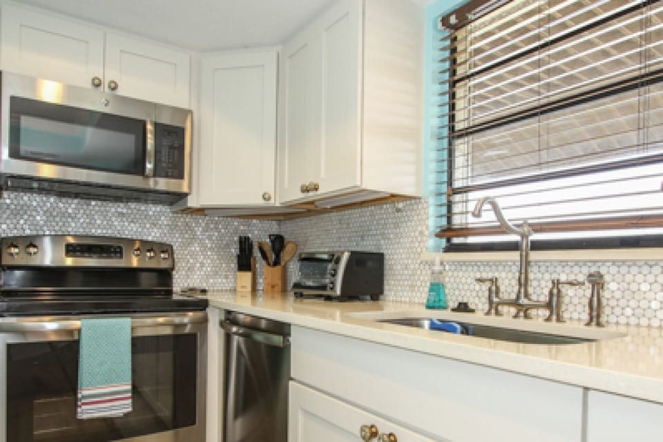 Custom backsplash tile design & quartz counters in well appointed kitchen