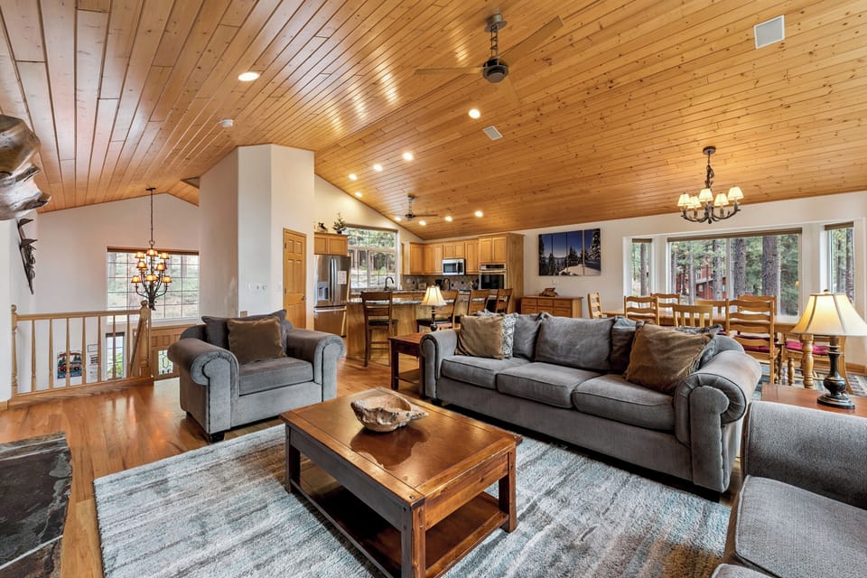 Relax in your spacious open-concept living area with soaring wood ceilings, cozy seating, and seamless flow to the fully-equipped kitchen.