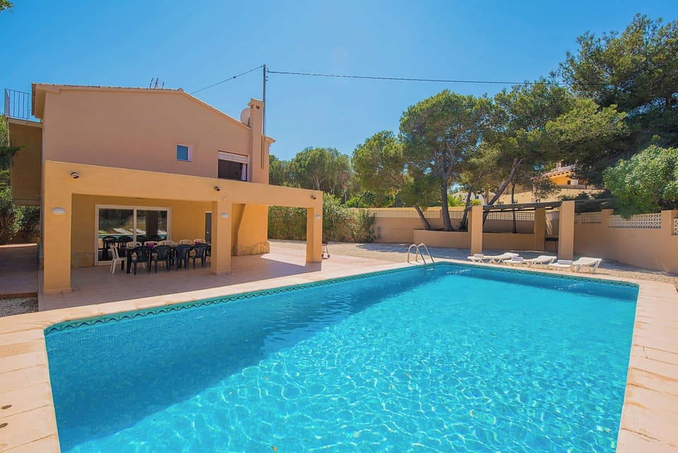Angenehme Sommervilla mit privatem Pool in Moraira (Costa Blanca) für 14 Personen, mit sieben Schlafzimmern und vier Badezimmern, auf zwei unabhängige Etagen, welche durch Außentreppen verbunden sind.INNENAUSSTATTUNG: Diese Villa besteht aus dem ERDGESCHOSS, in dem sich ein Wohn-Esszimmer mit Zugang zur überdachten Terrasse und zum Pool befindet. Eine voll ausgestattete Küche mit Gasherd und Geschirrspüler. Drei Schlafzimmer, zwei davon mit je zwei Einzelbetten und eines mit einem Doppelbett. Auch gibt es zwei Badezimmer, eines mit Badewanne und das andere mit Dusche. Im OBERGESCHOSS gibt es ein Wohn-Esszimmer mit SAT TV/TDT, vier Schlafzimmer, zwei davon mit je zwei Einzelbetten und zwei mit je einem Doppelbett. Ein Badezimmer mit Badewanne und schließlich ein Badezimmer mit Dusche.AUSSENBEREICH: Großes Grundstück mit einem 10x5 Pool mit Metalltreppe und viel Platz um in den Liegen die Sonne zu geniessen. Es gibt auch einen überdachten Grill um Mahlzeiten im Freien einzunehmen und Parkplatz auf demselben Grundstück für vier Fahrzeuge.LAGE: Nur 900 m bis zum Sandstrand von Moraira und 700 m zu den nächsten Restaurants. Der nächste Supermarkt ist in 1,5 km erreichbar, ebenso das Stadtzentrum von Moraira. Calpe ist 13 km entfernt.BEMERKUNGEN: Es gibt kein Internet. Haustiere bis 12 kg sind gegen Aufpreis erlaubt.