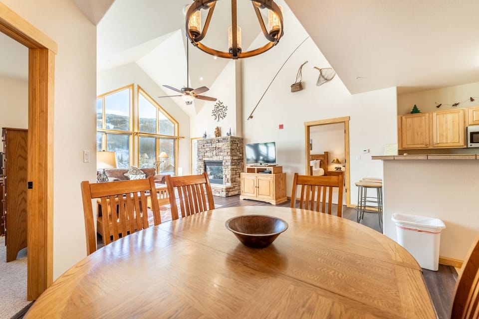 Gather around this beautiful dining table where warm wood and soaring ceilings create the perfect space for memorable meals together.