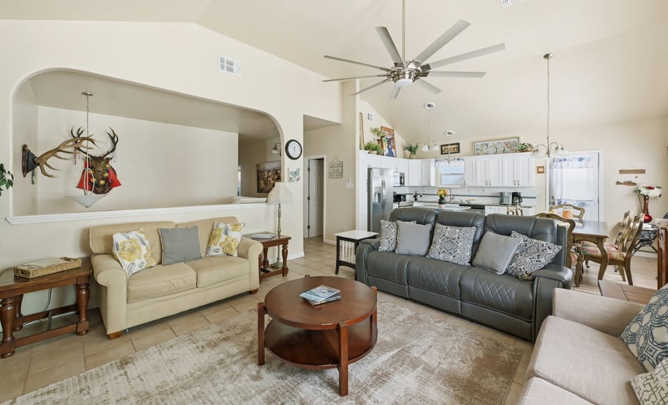 Living room — cream & leather sofas with deer mount in arched niche, kitchen beyond