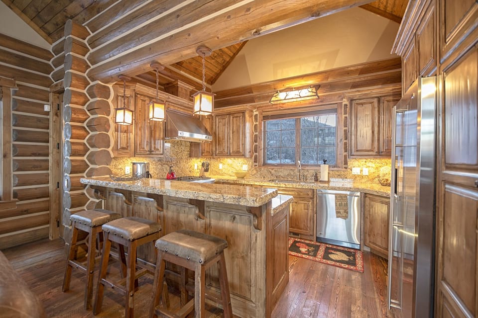 Step into your dream rustic kitchen where warm wood embraces you from floor to ceiling. You'll love preparing meals with granite countertops, premium appliances, and cozy pendant lighting creating the perfect mountain retreat atmosphere.