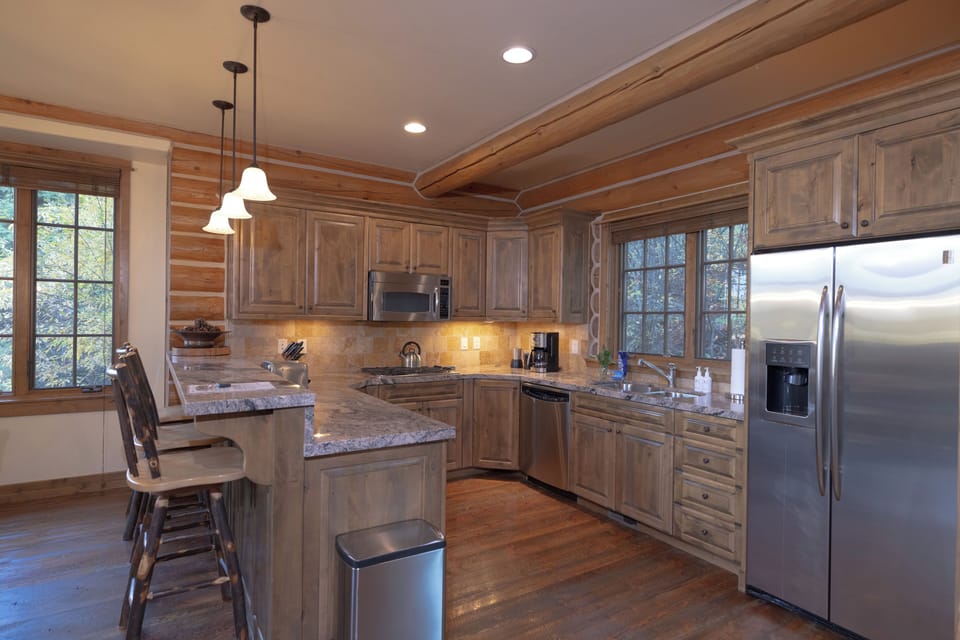 Your rustic-modern kitchen awaits with warm wood cabinets, granite counters, and stainless steel appliances. Natural light floods through large windows as you sip morning coffee at the island breakfast bar.