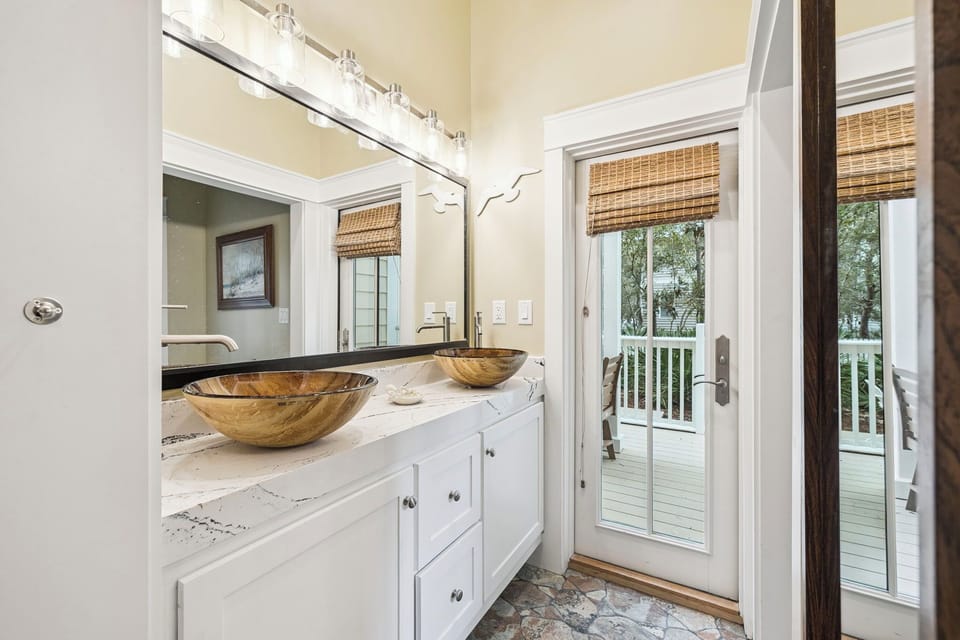 Pamper yourself in this elegant bathroom featuring stunning golden vessel sinks, marble countertops, and French doors opening to your private balcony.