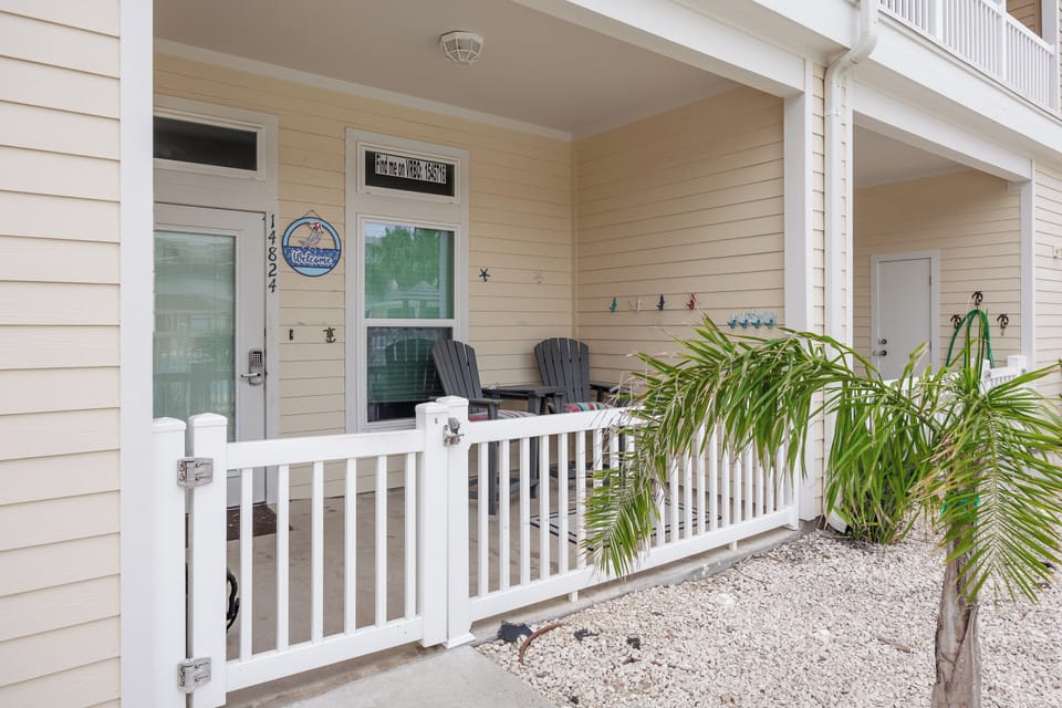 Your welcoming front porch with comfortable Adirondack chairs and tropical palms creates the perfect spot to unwind.