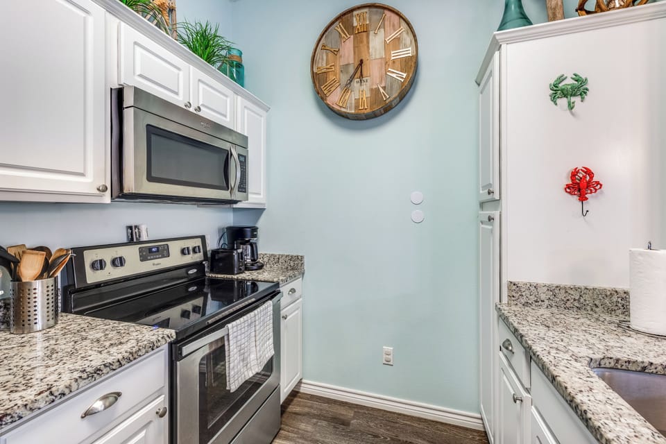 Cook your favorite meals in this fully equipped galley kitchen with granite counters, modern appliances, and coastal charm.