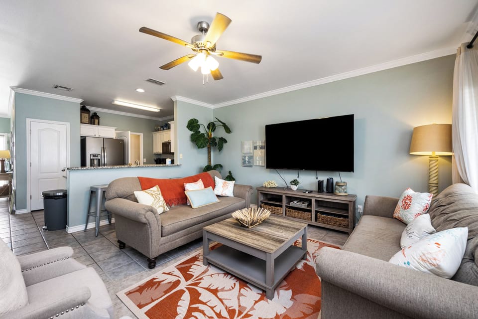 Relax in your stylish living room with comfortable seating, large TV, and open kitchen—perfect for unwinding after your adventures.