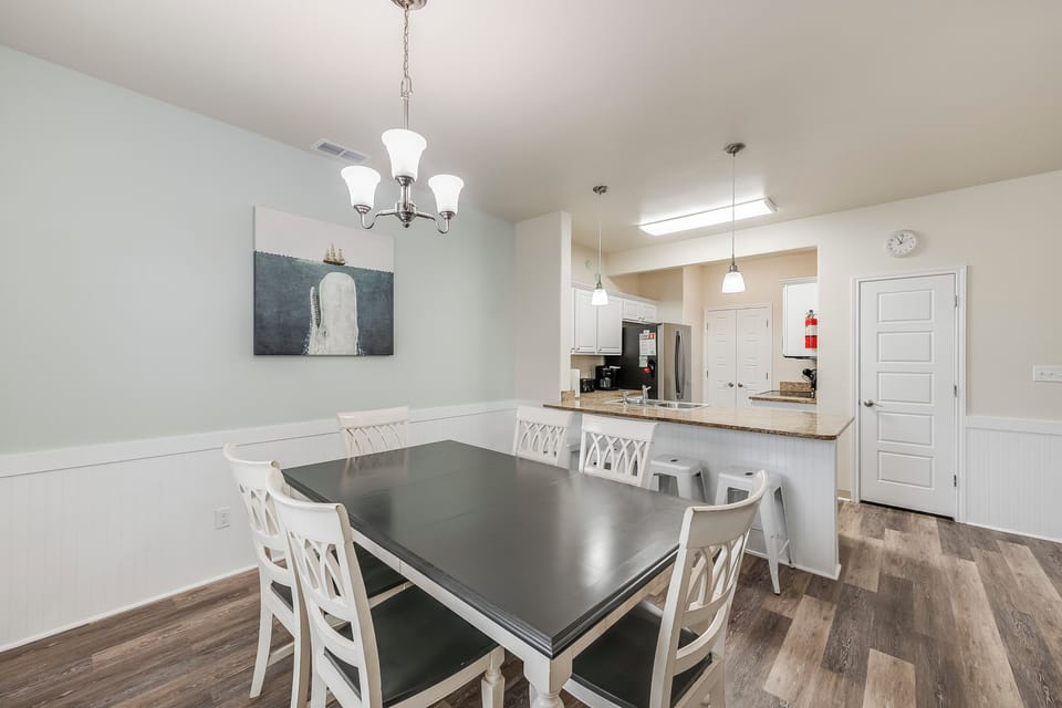 Gather around this spacious dining table where memorable meals and conversations await, with your fully equipped kitchen just steps away.