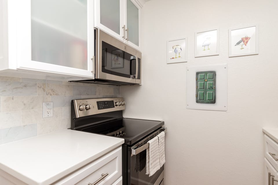 Your fully equipped kitchen features modern stainless steel appliances and elegant white cabinets, perfect for preparing meals during your stay.