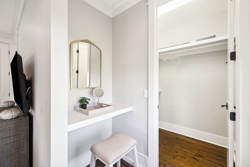 Your private vanity nook invites morning rituals, with soft natural light highlighting the elegant arched mirror and calm neutral palette. Step inside to discover your walk-in closet.