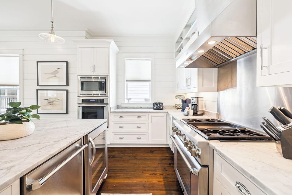 Picture yourself preparing meals in this bright, airy kitchen with gleaming marble countertops, professional-grade appliances, and beautiful wood flooring that adds warmth to your coastal retreat.